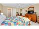 Bright main bedroom with a colorful quilt, ceiling fan, and wood dresser at 1536 Porpoise Rd, Venice, FL 34293