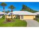 Charming single-story home with a well-maintained lawn, tropical palm trees, and a bright yellow exterior at 1614 Quail Lake Dr, Venice, FL 34293