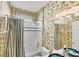 Bathroom with tub, shower, toilet, sink with green and blue sink, and jungle themed wallpaper at 1620 San Silvestro Dr, Venice, FL 34285
