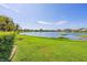 Scenic lake view from backyard with lush green grass and clear blue sky at 1620 San Silvestro Dr, Venice, FL 34285