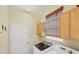 The laundry room is compact, featuring a washer, dryer, storage cabinets, and a window at 1620 San Silvestro Dr, Venice, FL 34285