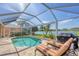Private pool area with lounge chairs, grill, screened enclosure and view of the lake at 1620 San Silvestro Dr, Venice, FL 34285