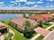 Lakeside home with beautiful terra cotta roof, manicured lawn, professional landscaping, and brick paver driveway at 20370 Grazie Pl, Venice, FL 34293
