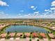 Expansive aerial view showcasing community homes surrounding a large lake on a sunny day with fluffy clouds at 20370 Grazie Pl, Venice, FL 34293