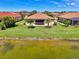 Backyard with lush green lawn, mature palm trees, a covered lanai, and waterfront views at 20370 Grazie Pl, Venice, FL 34293
