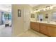 Bathroom with a double sink vanity, adjacent to a bedroom with a lake view at 20370 Grazie Pl, Venice, FL 34293