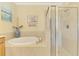Inviting bathroom showcasing a soaking tub with tile surround and a glass-enclosed shower at 20370 Grazie Pl, Venice, FL 34293