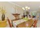 Well-lit dining room showcasing a wooden table, chandelier, and decorative sailboat accent at 20370 Grazie Pl, Venice, FL 34293