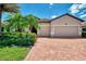 Home with manicured landscaping, brick driveway, and a secure ADT system near lush landscaping and a paver driveway at 20370 Grazie Pl, Venice, FL 34293
