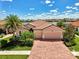 Charming single-Gathering home featuring a brick driveway, well-manicured lawn, and tropical landscaping by the lake at 20370 Grazie Pl, Venice, FL 34293