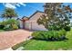 Single-Gathering home features a lush magnolia tree, brick driveway, and well-maintained landscaping near the lake at 20370 Grazie Pl, Venice, FL 34293