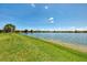Expansive lake view with lush green grass leading to the tranquil water's edge at 20370 Grazie Pl, Venice, FL 34293