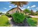 Home with manicured landscaping, tropical foliage, privacy hedges, and lush green lawn with lake in background at 20370 Grazie Pl, Venice, FL 34293