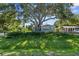 Charming home with a large tree providing shade, lush grass, and well-maintained landscaping at 2185 Park Rd, Venice, FL 34293