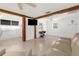 Open-concept living room with white floors, white walls, exposed beams, and natural light at 2185 Park Rd, Venice, FL 34293