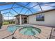 In-ground pool and spa combination surrounded by brick pavers in screened-in lanai at 2487 Marton Oak Blvd, North Port, FL 34289