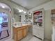 Well-lit bathroom featuring a vanity with storage, decorative mirror, and built-in shelving for ample storage space at 3139 Point St, North Port, FL 34286