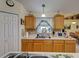 Kitchen with light wood cabinets, mosaic tile backsplash, and double sink under the window at 3139 Point St, North Port, FL 34286