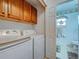 Bright laundry room with white washer/dryer, wooden cabinets and adjacent bathroom at 3139 Point St, North Port, FL 34286