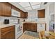 Cozy kitchen features wood cabinets, white appliances, and bright overhead lighting at 330 Mission N Trl # B, Venice, FL 34285