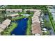 Aerial view of the condo community, showcasing the pond, pool, landscaping, and carports at 330 Mission N Trl # F, Venice, FL 34285