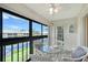 Enclosed balcony features serene pond views, seating for four, and door to outside at 330 Mission N Trl # F, Venice, FL 34285