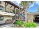 Inviting condo entrance featuring well-maintained landscaping, outdoor staircase and covered parking at 330 Mission N Trl # F, Venice, FL 34285