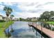 Tranquil water view of a wooden dock on the community pond surrounded by tropical palms at 330 Mission N Trl # F, Venice, FL 34285
