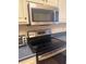 Close-up view of the kitchen with stainless steel microwave, oven, cooktop, and brick backsplash at 3697 Lake Bayshore Dr # H-109, Bradenton, FL 34205