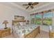 Relaxing bedroom with bamboo furnishings, palm-themed bedding, and large window with golf course views at 371 Capulet Dr, Venice, FL 34292