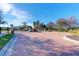 Gated community entrance with brick-paved driveway and meticulously maintained landscaping under a bright blue sky at 371 Capulet Dr, Venice, FL 34292