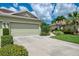 Charming home featuring an attached garage, concrete driveway, and lush tropical landscaping at 371 Capulet Dr, Venice, FL 34292