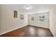 Bright bedroom with three windows, beautiful dark laminate floors, and neutral paint at 386 Nightingale Rd, Venice, FL 34293