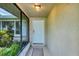 Screened entryway featuring a textured wall, white front door, and decorative greenery, offering a welcoming entrance at 386 Nightingale Rd, Venice, FL 34293