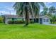 Charming single-story home featuring a lush green lawn and a mature palm tree in the front yard at 386 Nightingale Rd, Venice, FL 34293