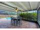 Screened-in patio with brick flooring, ceiling fan, and table overlooking the pool and backyard at 386 Nightingale Rd, Venice, FL 34293