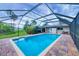 Backyard featuring screened in-ground pool, brick patio, and lush landscaping at 386 Nightingale Rd, Venice, FL 34293