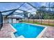 Sparkling in-ground pool with screened enclosure and brick paver deck, surrounded by a privacy fence at 386 Nightingale Rd, Venice, FL 34293