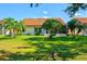 Lush backyard featuring a well-kept lawn, tropical palm trees, and a charming, inviting home exterior at 4114 Murfield E Dr, Bradenton, FL 34203