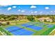 Aerial view of vibrant blue tennis courts surrounded by greenery and houses, offering a picturesque recreational setting at 4114 Murfield E Dr, Bradenton, FL 34203