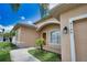 Home exterior showcasing an arched entryway, well-kept lawn, and a lush palm tree at 4150 Otoole St, North Port, FL 34291