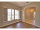 Living room with shuttered windows and wood-look flooring that leads to an arched doorway and bathroom at 4150 Otoole St, North Port, FL 34291