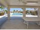 View from a screened porch shows a community pool with poolside seating amid lush tropical landscaping at 4831 Summertree Rd, Venice, FL 34293