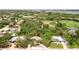 Aerial view of the home showcases its location in a verdant, tree-filled neighborhood near a green sports field at 5369 Shadow Lawn Dr, Sarasota, FL 34242