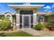 Charming home exterior with a screened-in porch and stone pathway amidst lush landscaping at 5818 Harrison Rd, Venice, FL 34293
