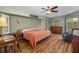 Bright main bedroom with wood-look flooring, a ceiling fan, and a view to the lanai at 5818 Harrison Rd, Venice, FL 34293