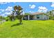 Spacious backyard with healthy green grass, young trees and exterior view of screened lanai at 5954 Gottfried Ln, North Port, FL 34291