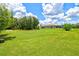 Expansive backyard with lush green grass, mature trees, and a screened-in patio visible on the house at 5954 Gottfried Ln, North Port, FL 34291