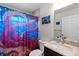 Bathroom features a granite countertop, an octopus shower curtain, and nautical-themed art at 5954 Gottfried Ln, North Port, FL 34291