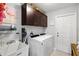 This laundry room has dark wood cabinets, a utility sink, and a white front load washer and dryer at 5954 Gottfried Ln, North Port, FL 34291
